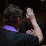 priest touching man's forehead